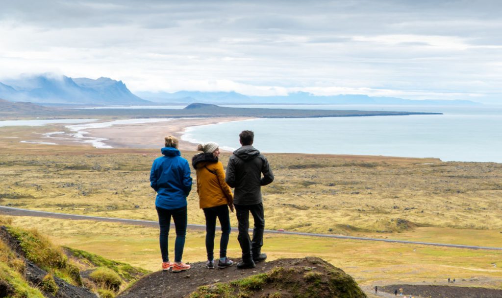 3 people standing on hill looking out at Icelandic landscape