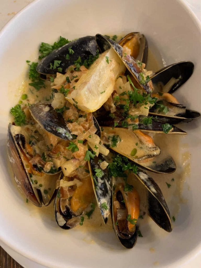 mussels with a lemon wedge in a white bowl