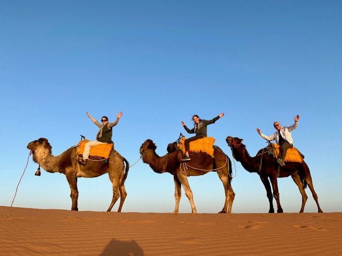 Riders on camels with hands up in the air