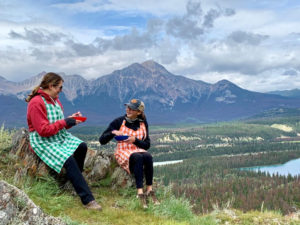 mom and daughter eating picnic on mountain top in Jasper