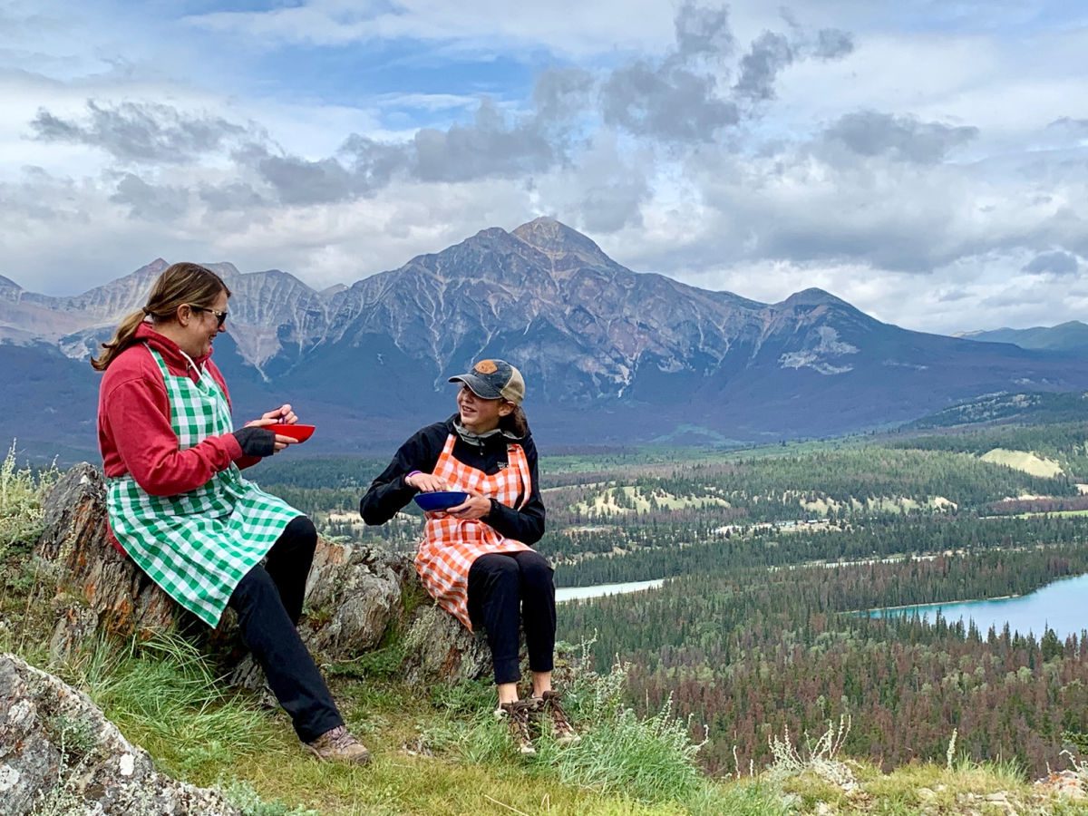 mom and daughter eating picnic on mountain top in Jasper