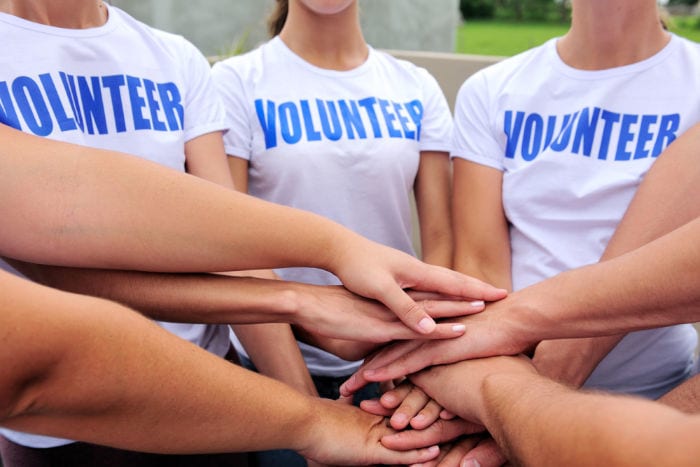 teen volunteers stacking hands