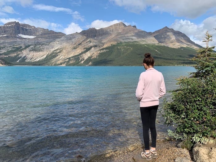 girl in pink sweatshirt and black pants near lake