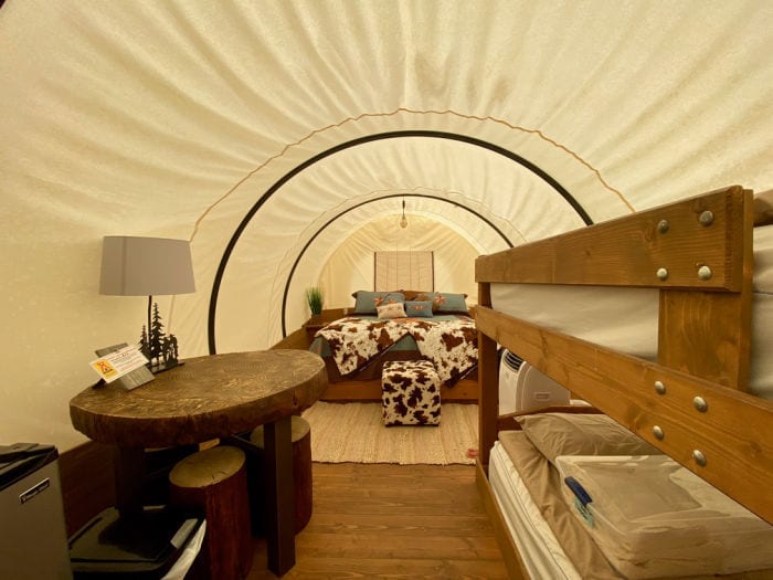 Bed, bunkbeds and table inside Conestoga glamping wagon