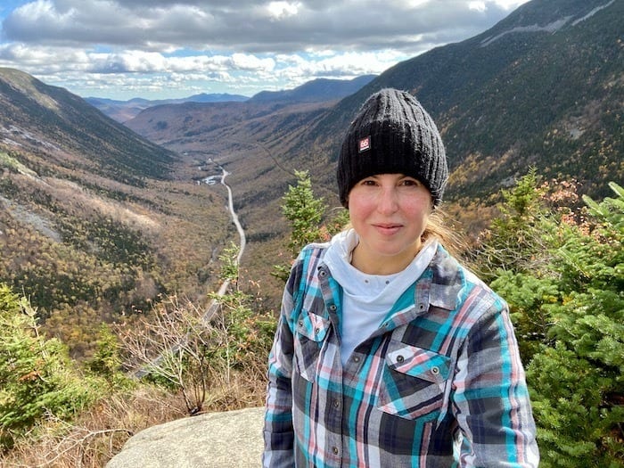 Woman in plaid shirt and black 66 North knit hat at overlook at top of Mount Willard in New Hampshire