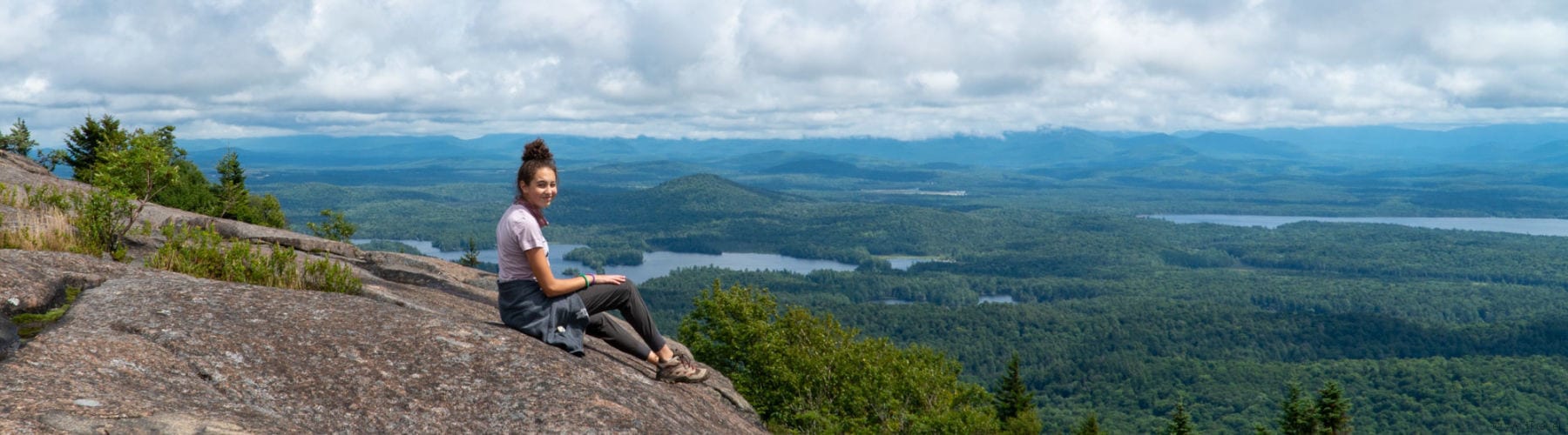 girl sitting on top of St Regis Mountain in the Adirondacks