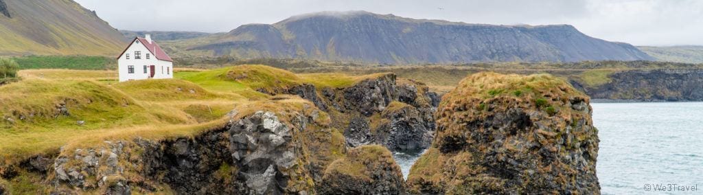 Arnarstapi rocks and white house on green grass in Iceland