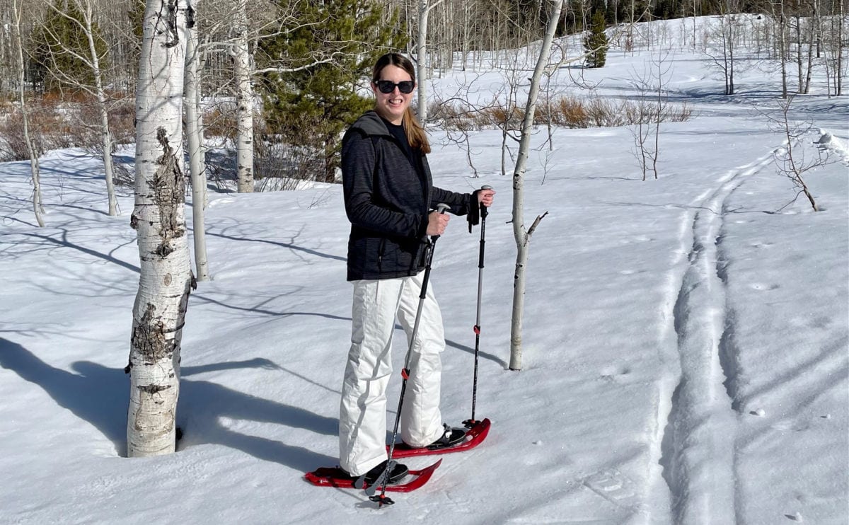 Woman in black jacket and white snow pants on snow shoes in the snow