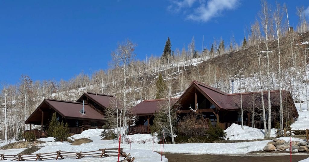 2 cabins in front of a snowy hill at the Vista Verde Ranch