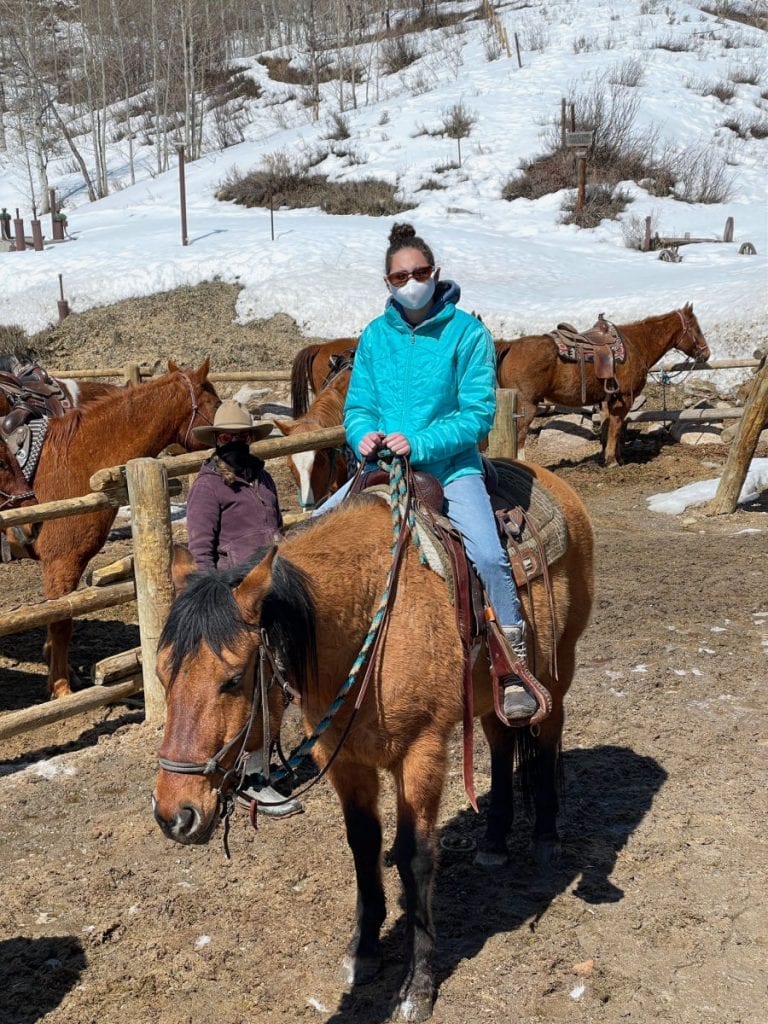 Girl in blue coat on horse in paddock