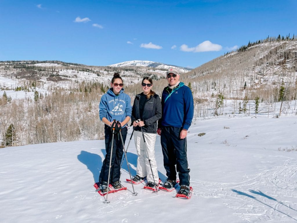 Family in snow shoes posing in front of the mountains