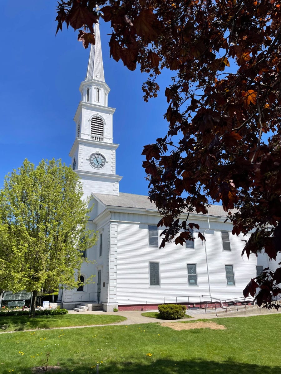 White church framed by trees and leaves