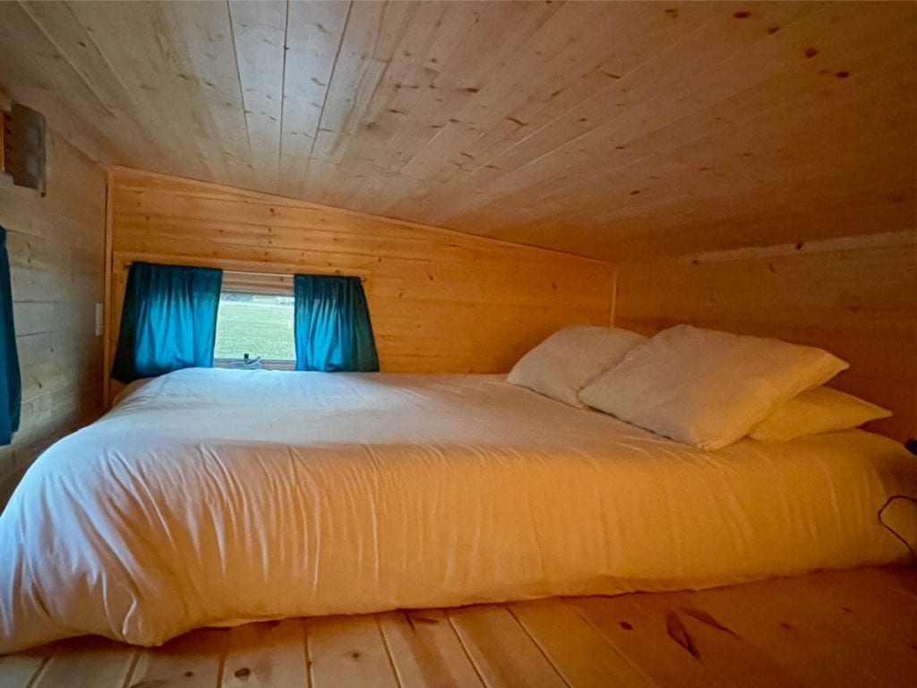 Emerson tiny house sleeping loft with a queen mattress on the wood floor