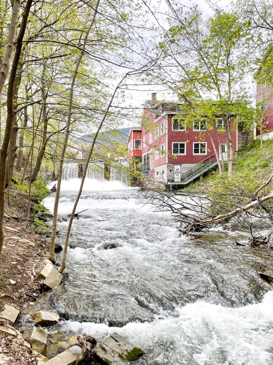 Waterfall and river next to red mill building in downtown Manchester Vermont