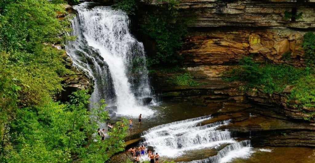 Cummins Falls waterfall with people swimming (Canva)