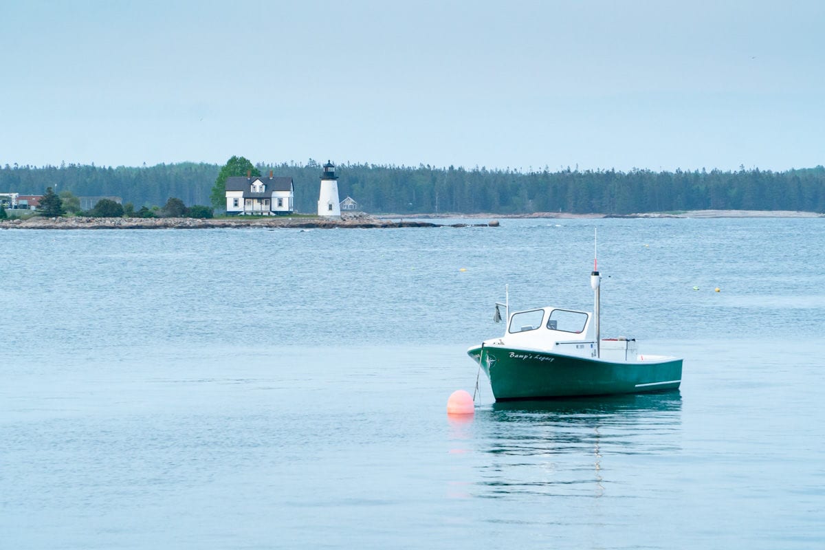 Green boat in the water in front of Prospect Harbor lighthouse