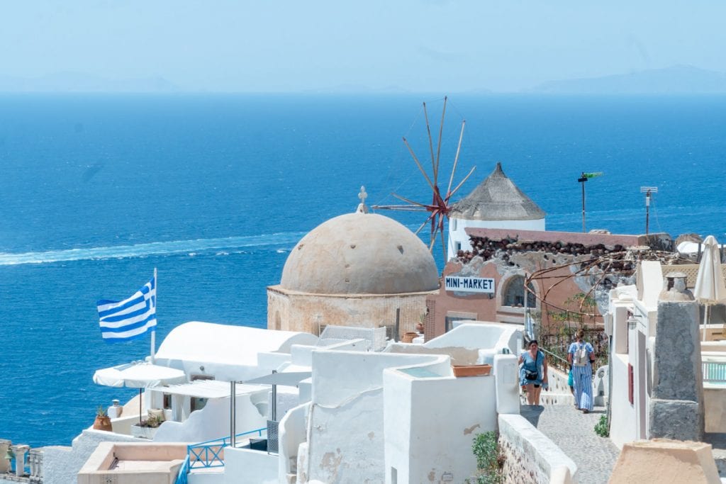 Windmill, domed church and Greece flag in Oil Santorini