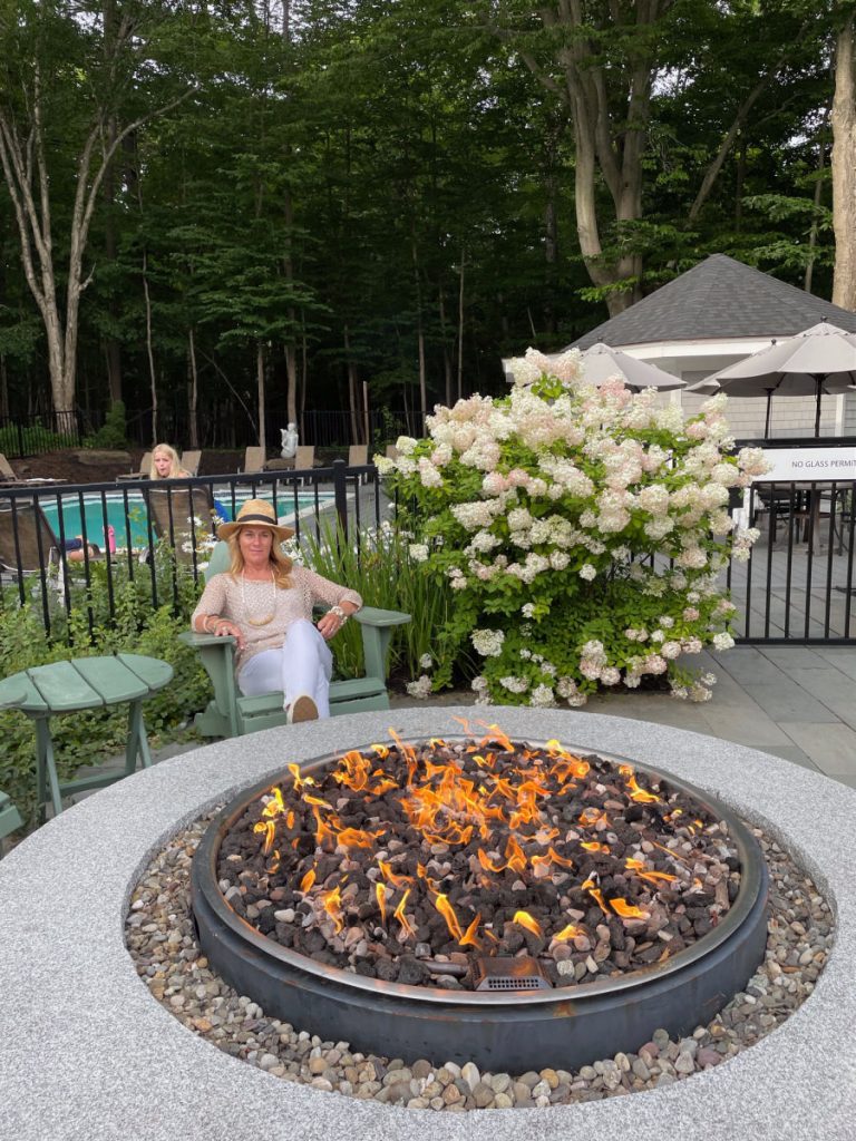 woman sitting by fire pit in front of a pool