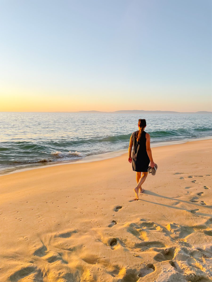 woman walking on a beach at sunset
