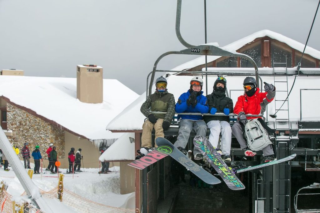 Four people on a ski chairlift in the snow at Beech Mountain