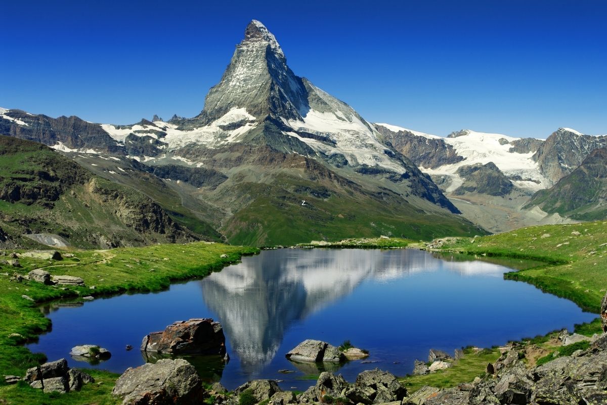 Matterhorn behind a blue lake and green fields in Switzerland