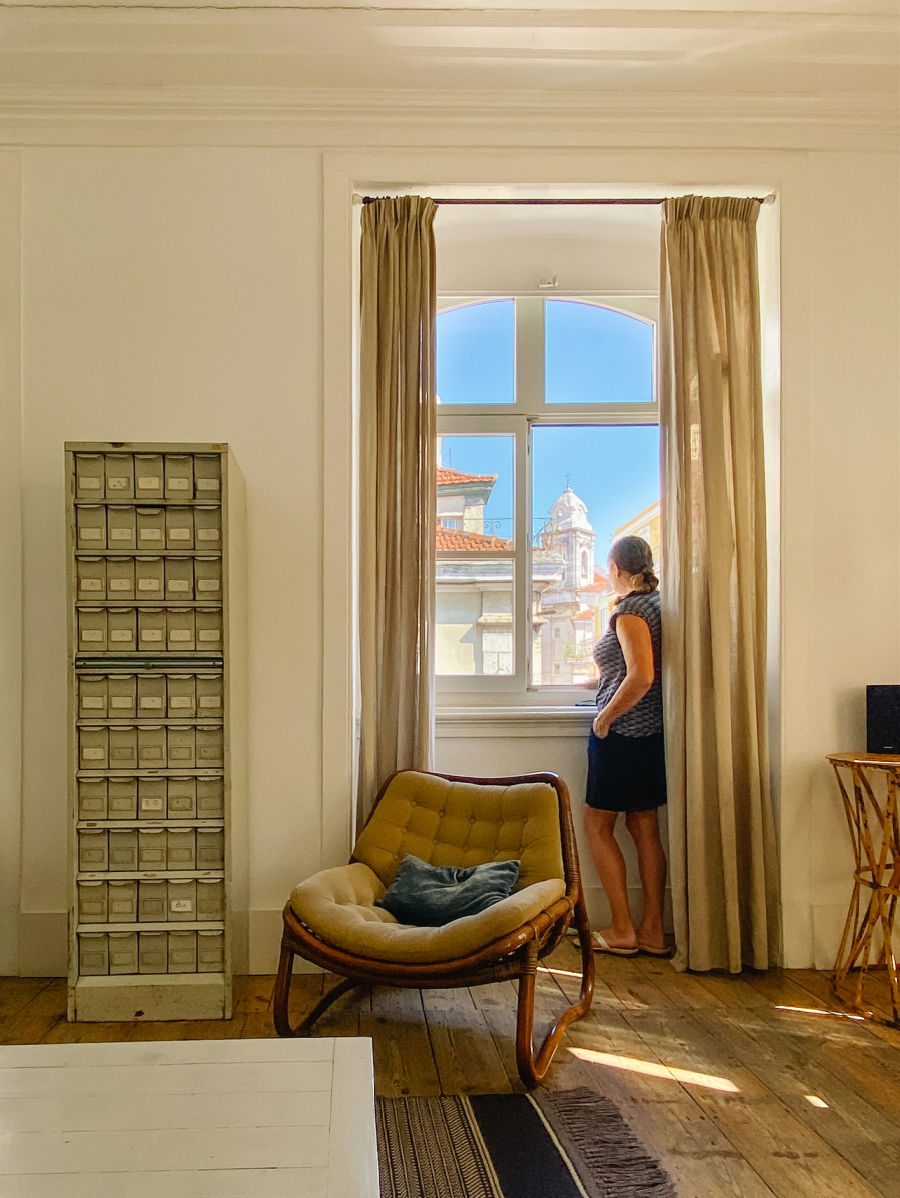 Woman standing by window in apartment at Baixa House
