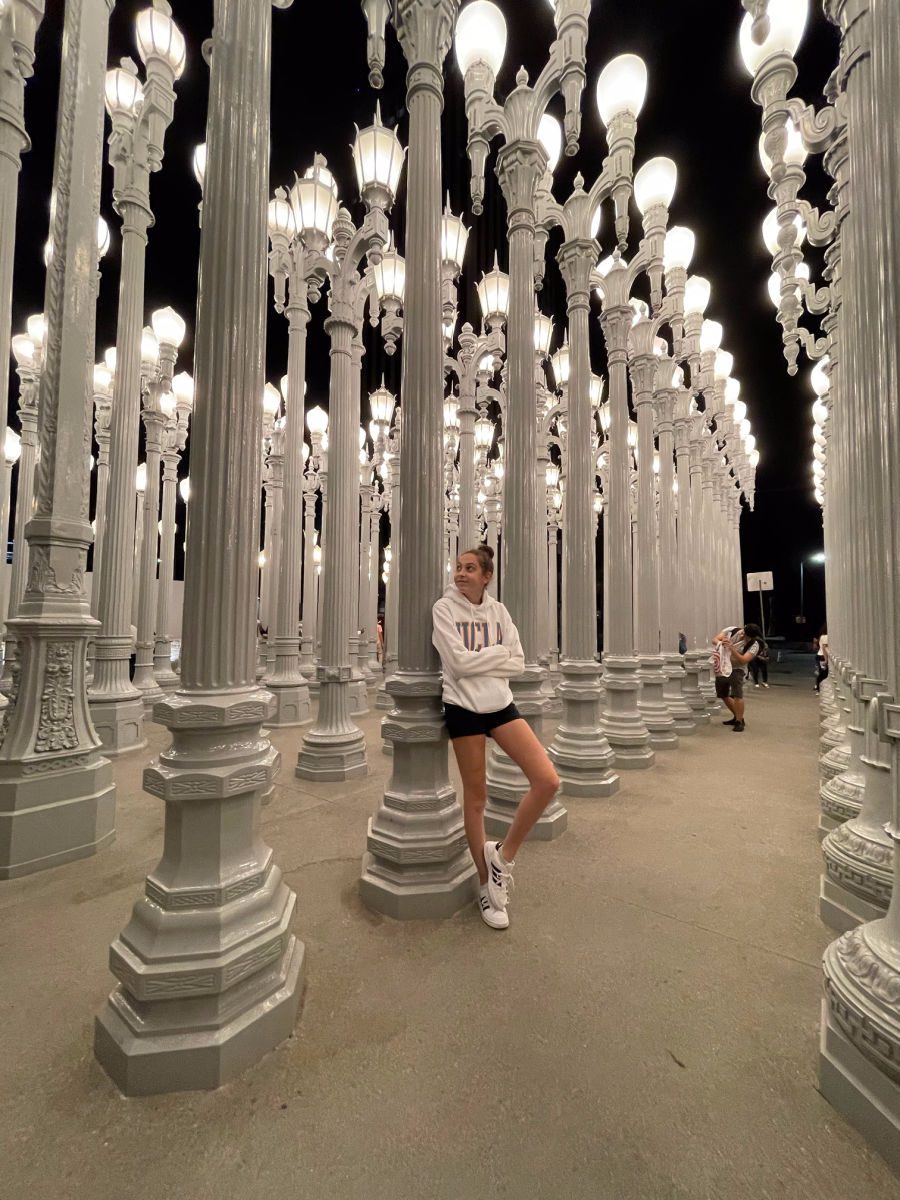 Girl in white UCLA sweatshirt leaning against white lamp posts outside of LACMA museum