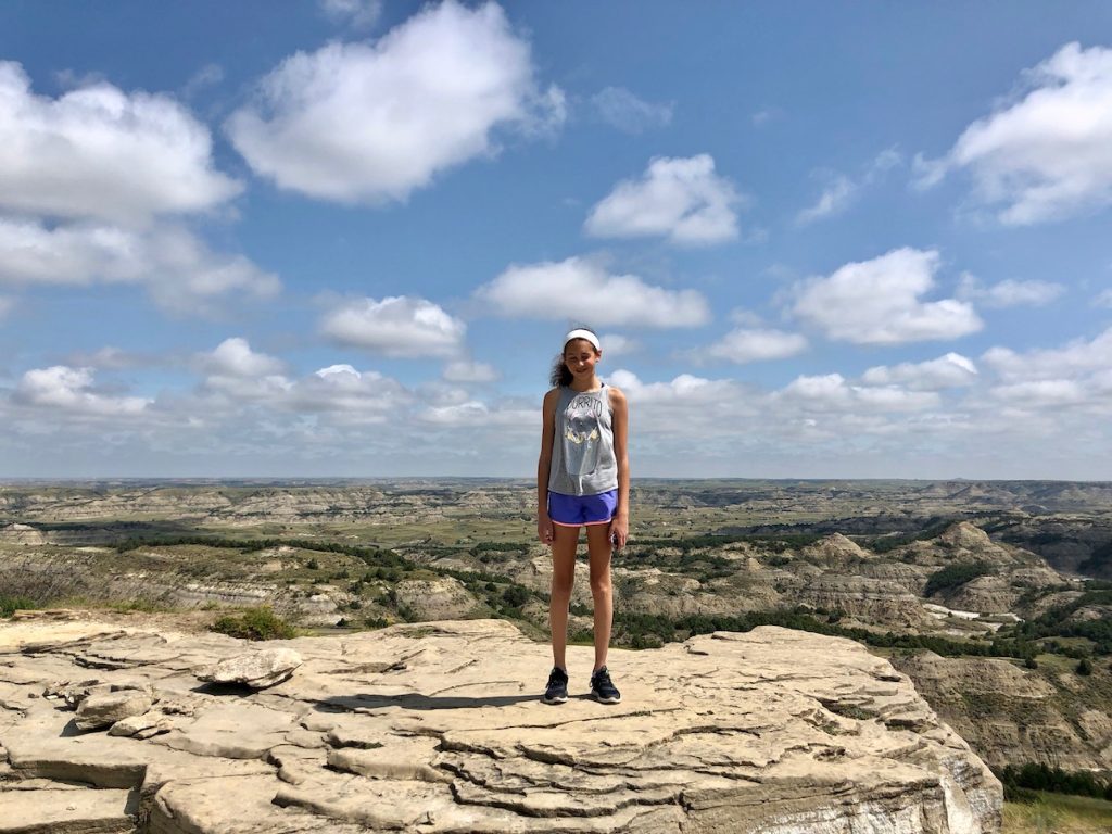Teen standing on cliff in Theodore Roosevelt National Park with badlands in the background