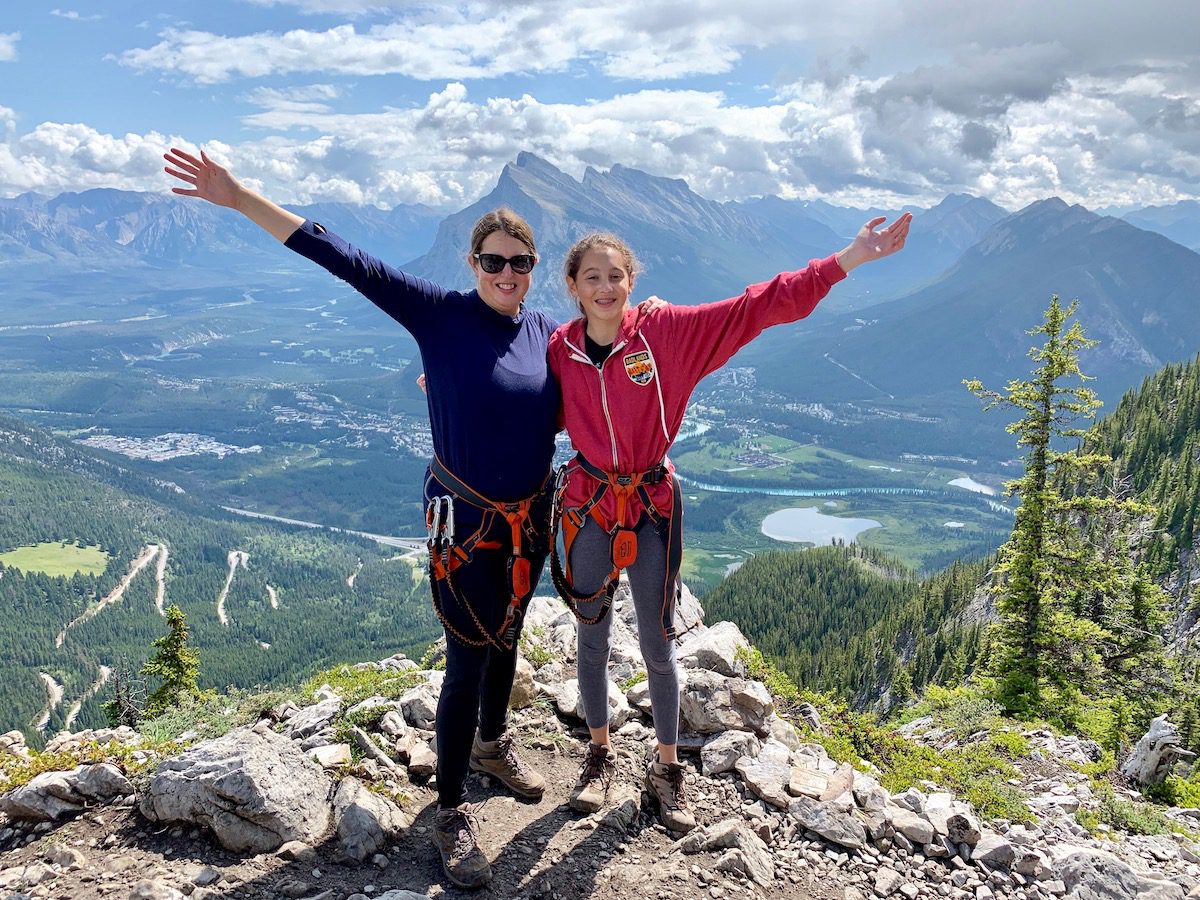 Mom and daughter on top of mountain with arms up