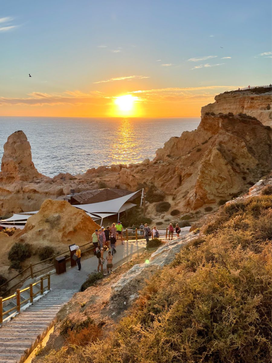 Sunset over water with golden cliffs and walkway