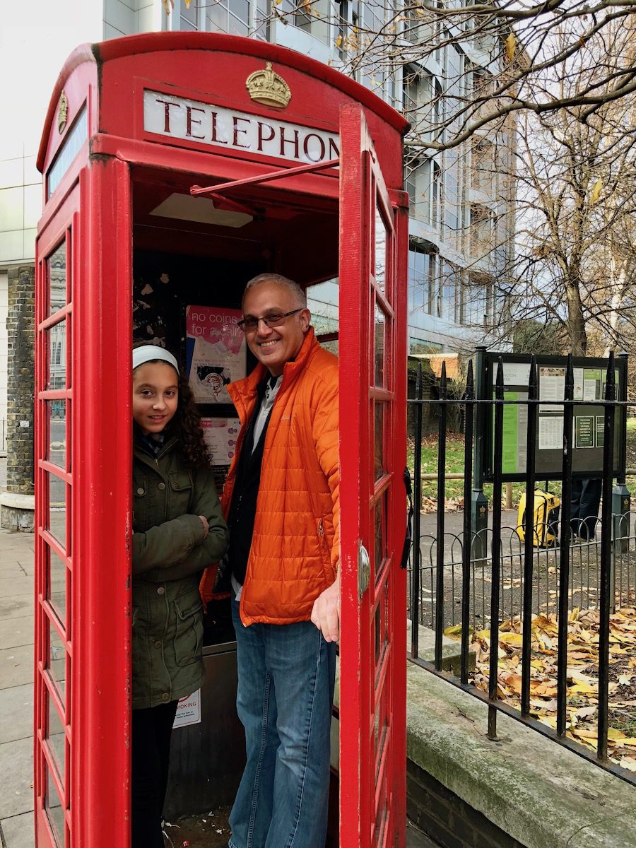 Girl and dad in a red telephone booth in London