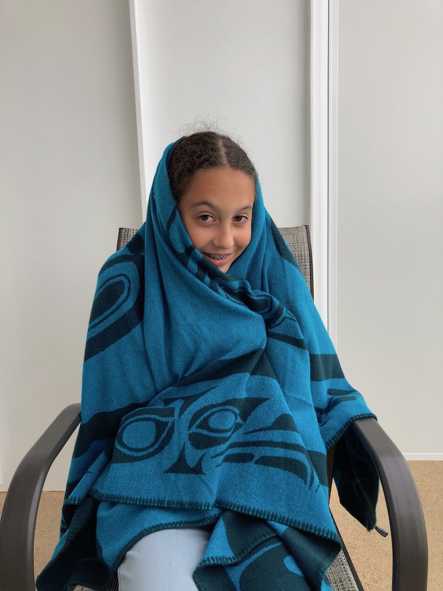 girl sitting wrapped in blue and black blanket