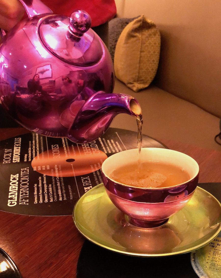 Pouring tea from a shiny pink tea kettle
