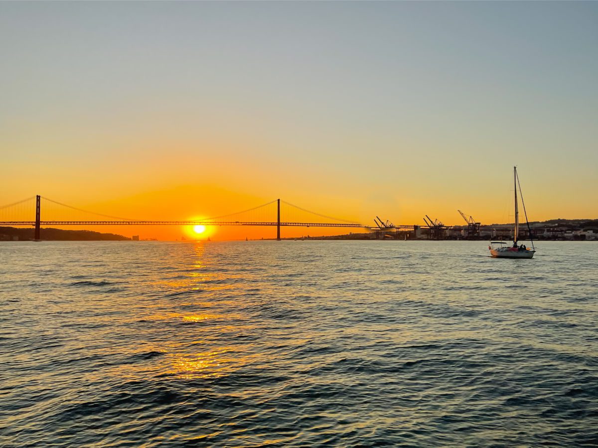 Tagus river bridge and sailboat at sunset