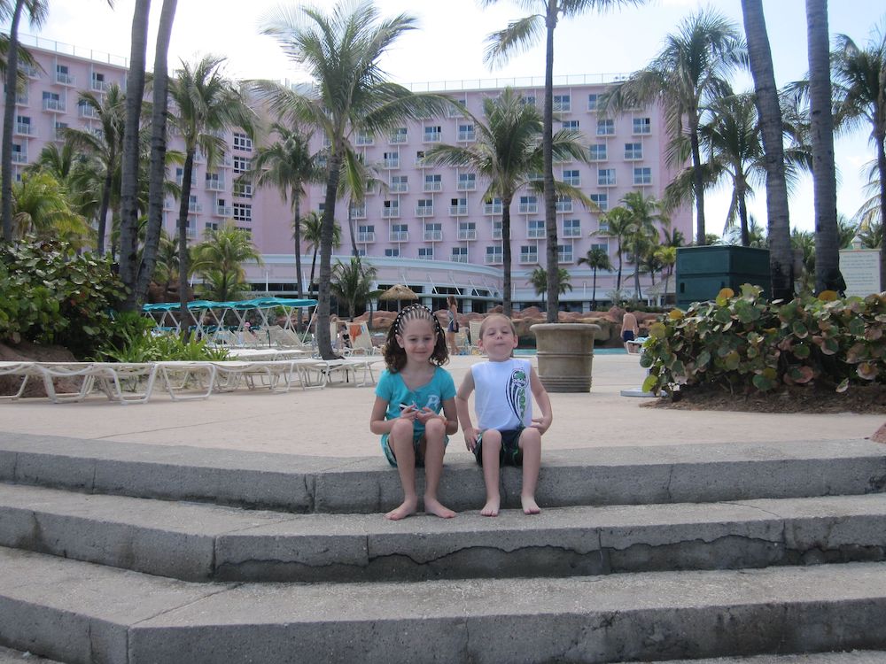 2 kids sitting on steps in front of pink coral tower at the atlantis