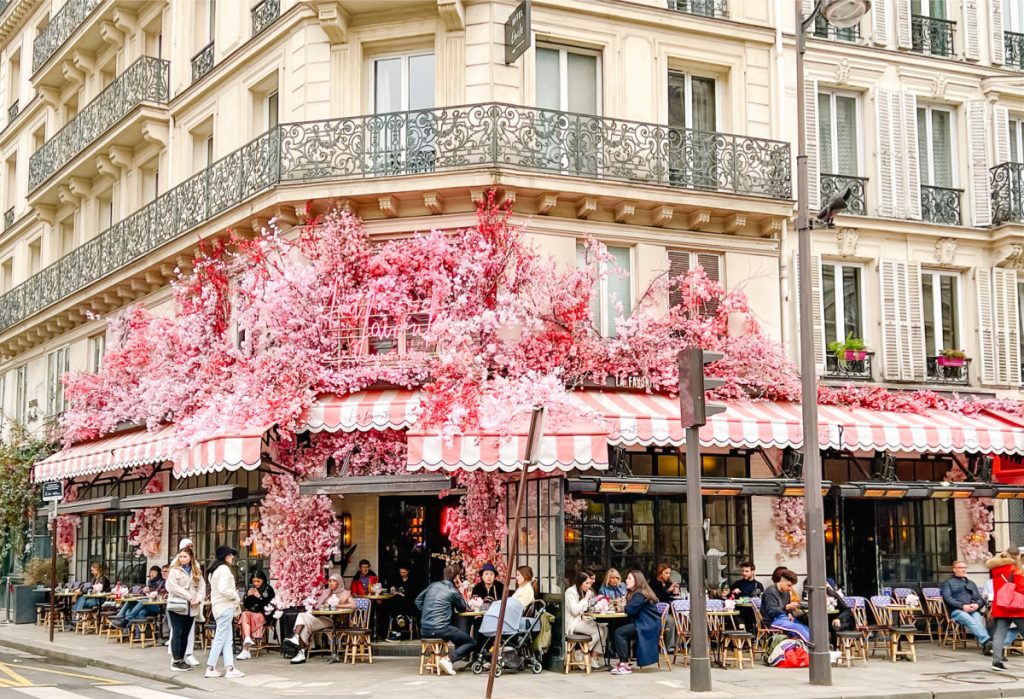 La Favorite cafe in Paris with pink flowers and pink and white striped awnings