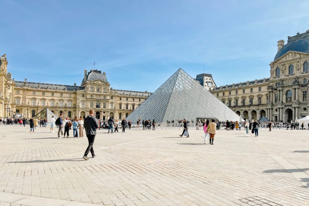 Louvre Museum glass pyramid with people walking