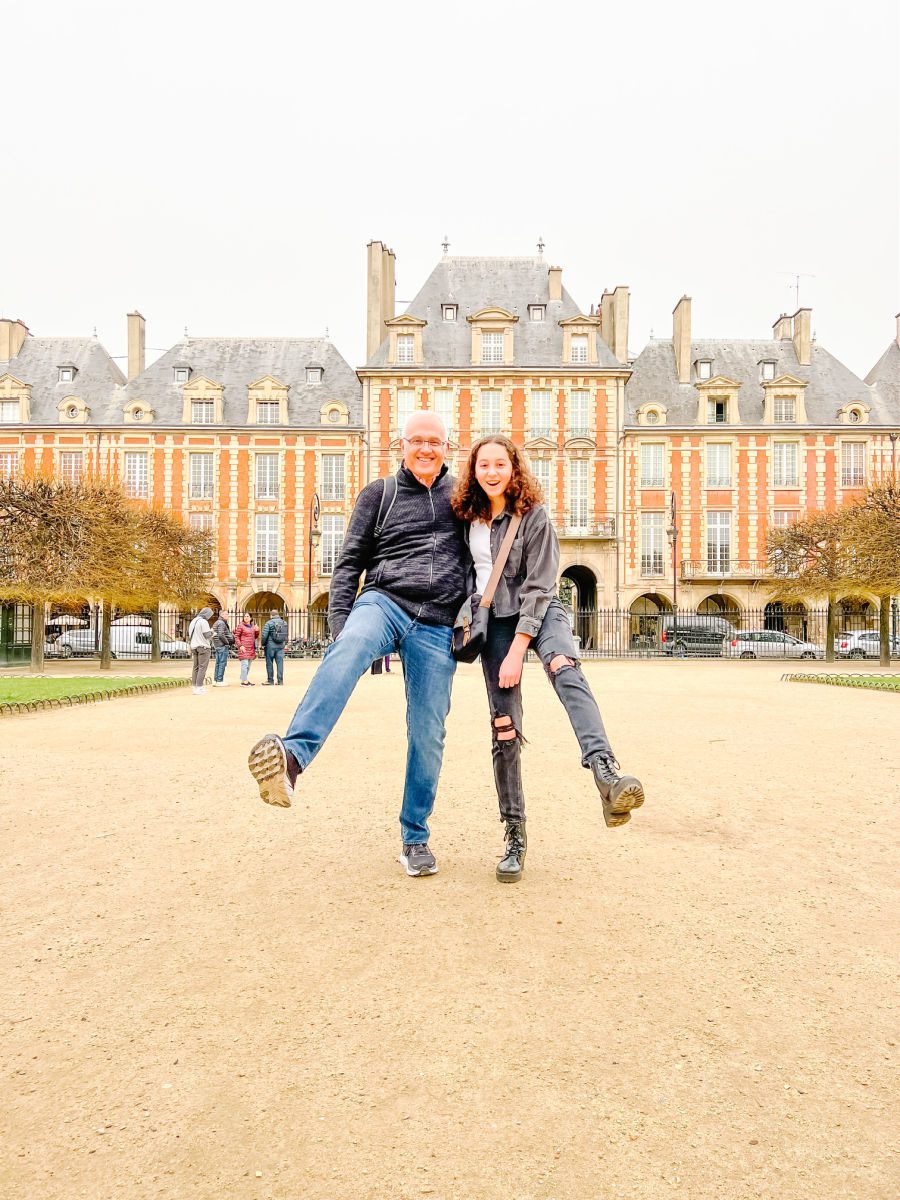 Father and daughter kicking up their feet in Place des Vosges