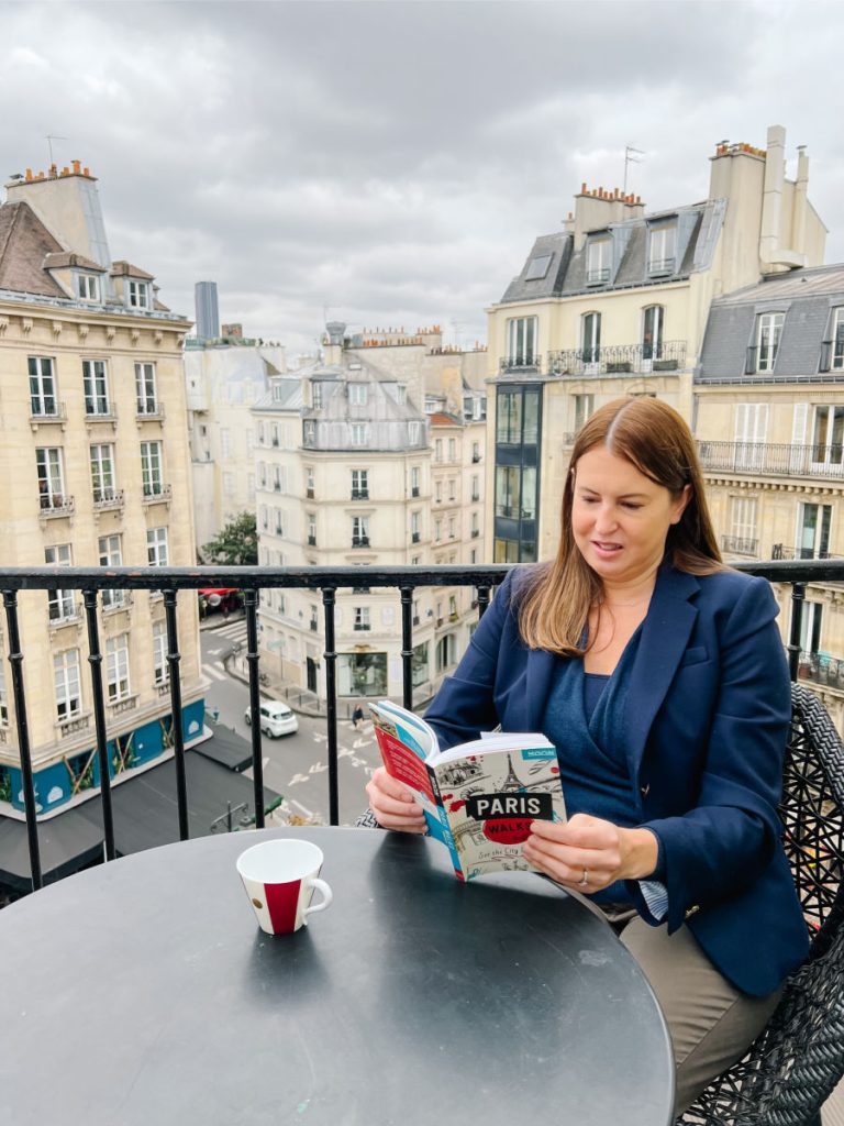 Woman reading guidebook on terrace overlooking Paris