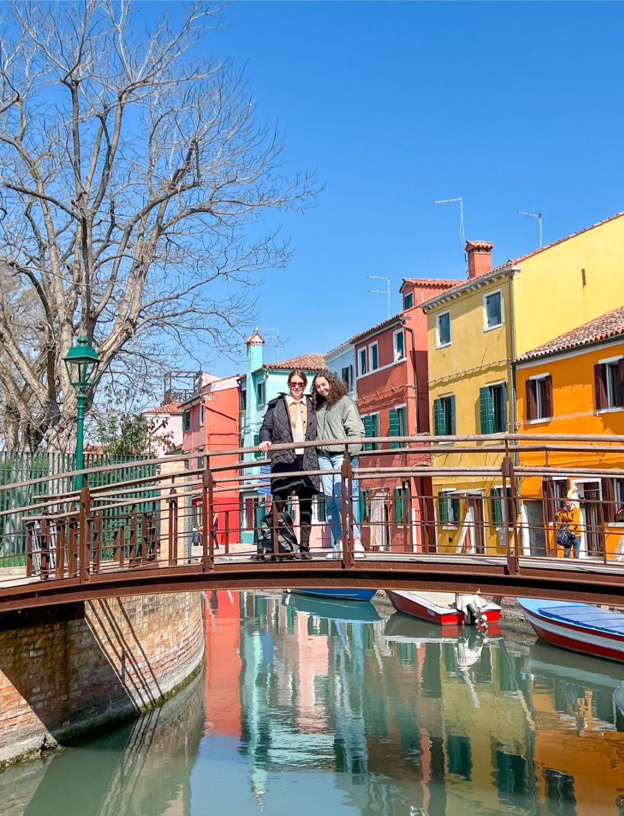 Mom and daughter on bridge with colorful houses in the background on Burano
