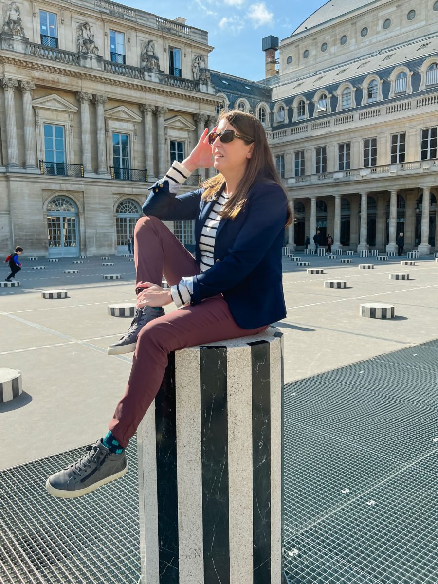 Woman on black and white striped column outside Palais Royal
