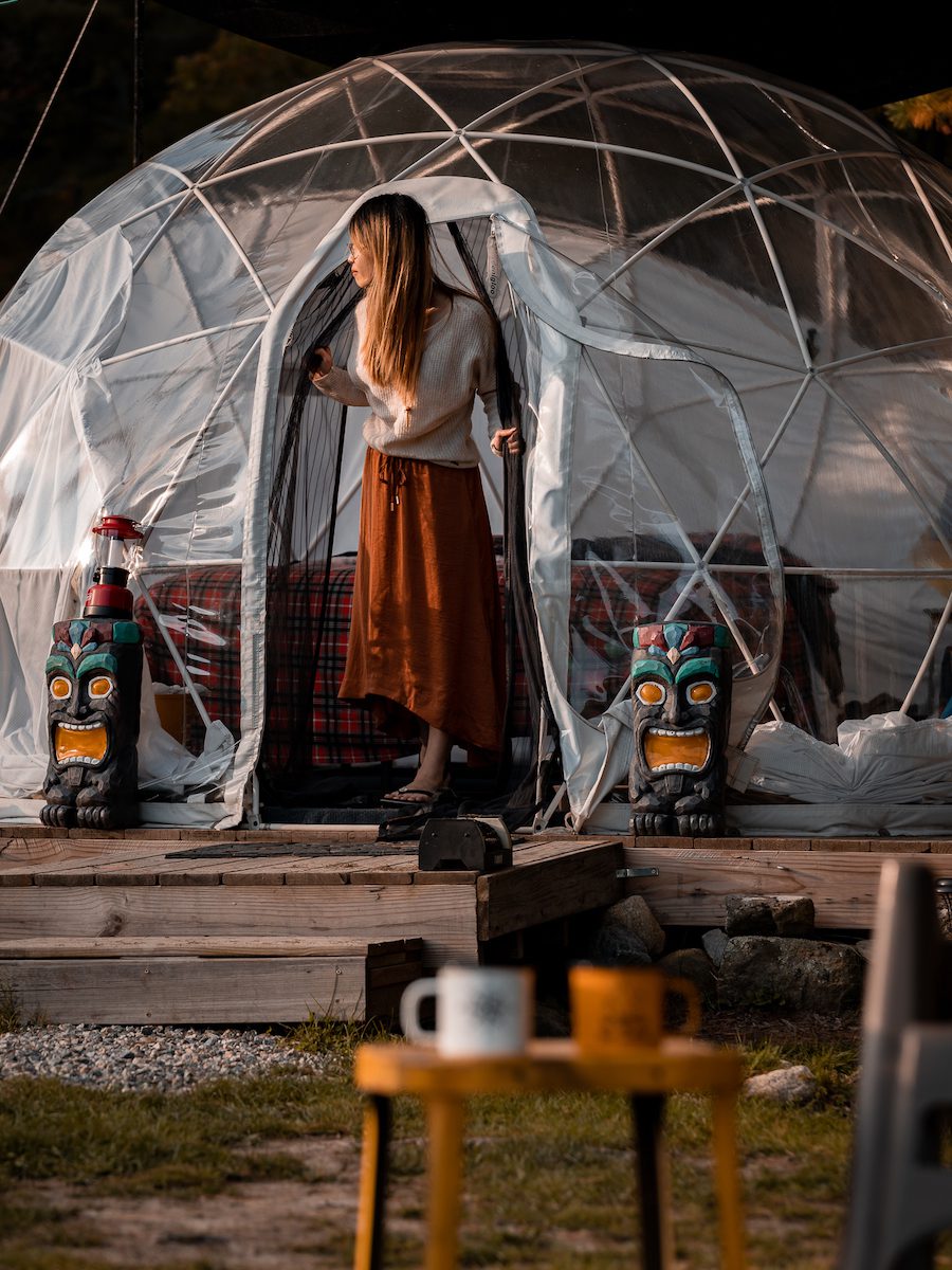 Woman exiting clear dome structure at night