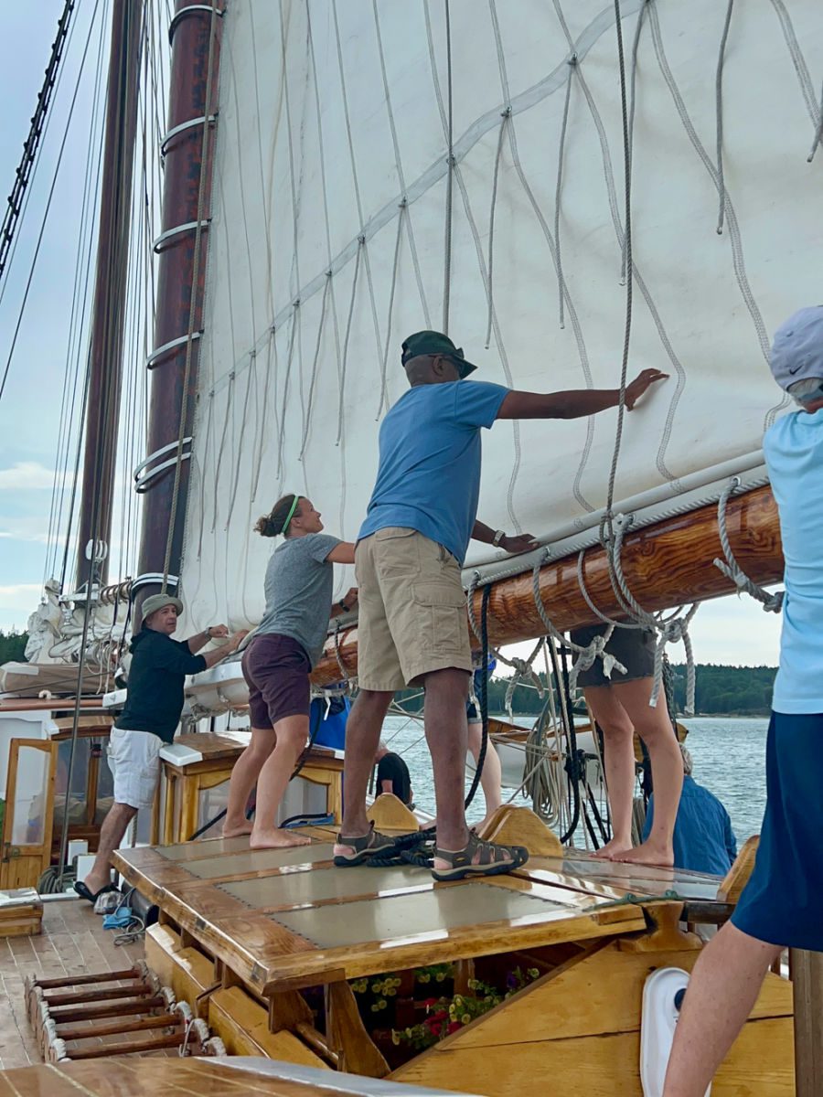 Passengers lowering and folding sails on the Schooner Heritage