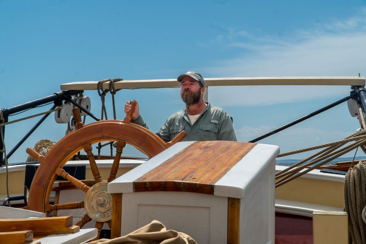 Captain Ben standing at the wheel of Schooner Heritage