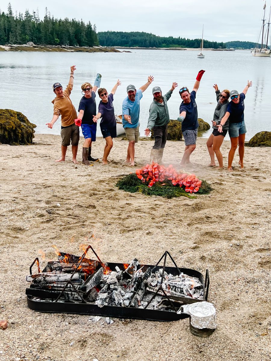 Crew of the Schooner Heritage with pile of lobsters and the fire on the beach