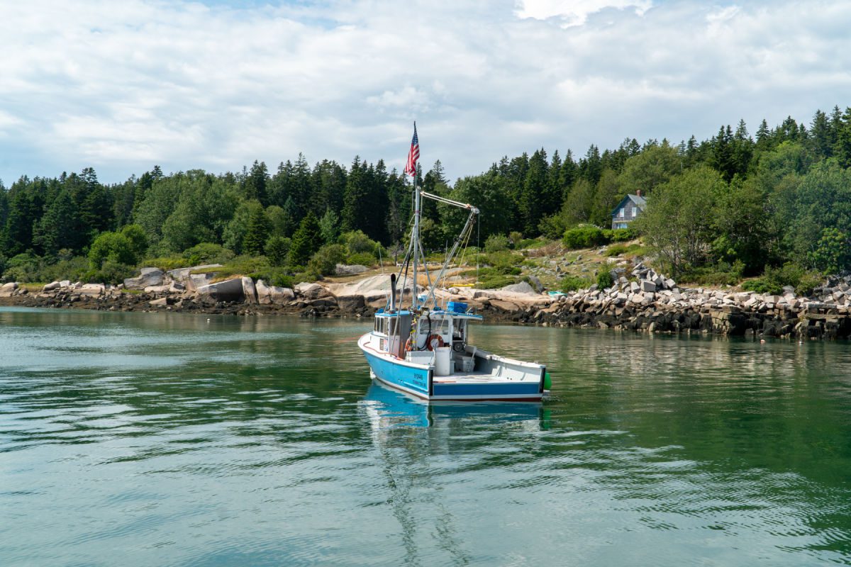 Blue lobster boat in front of an island in Maine