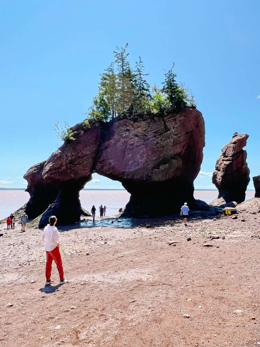 Flower Pot rocks with woman in front at high tide