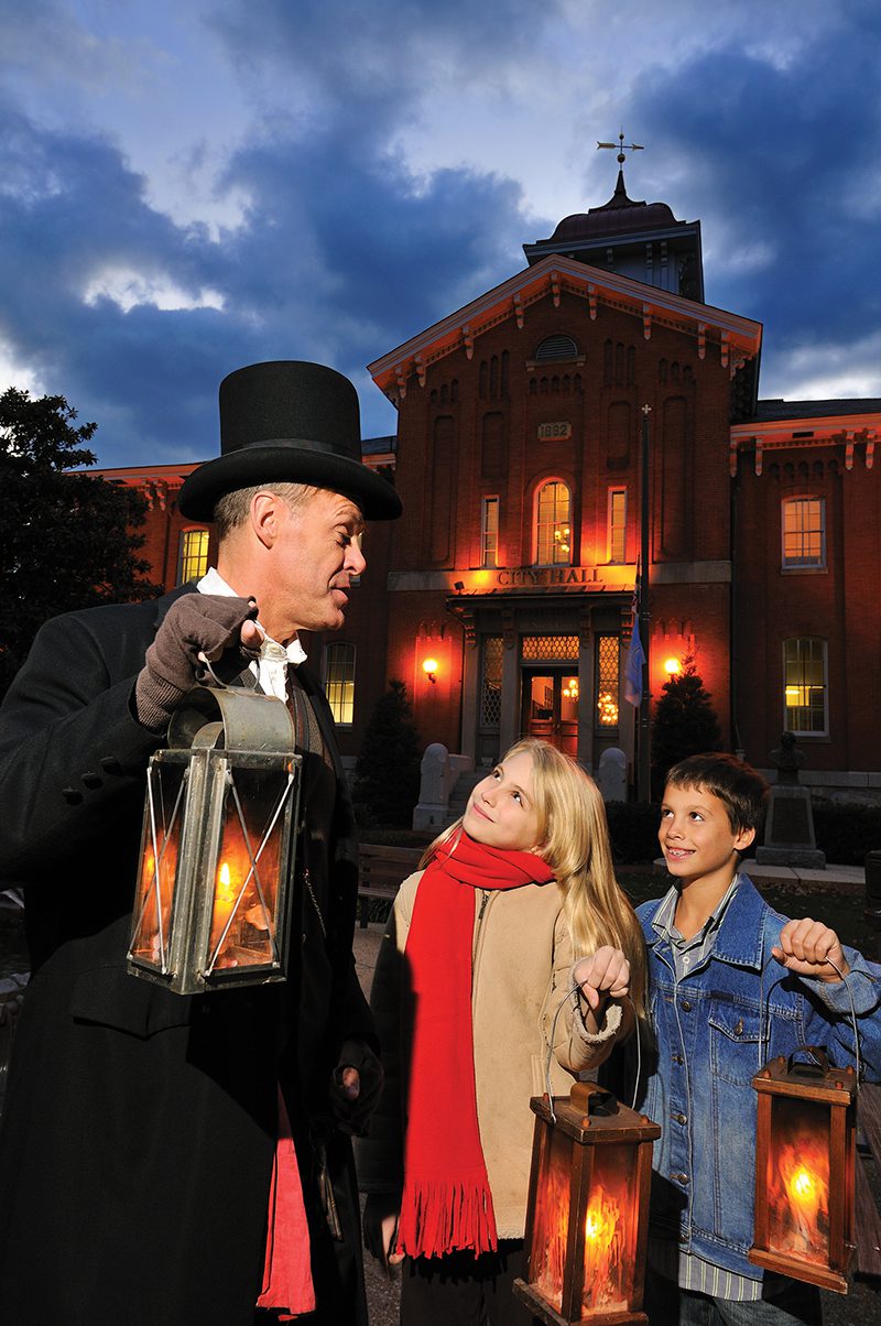 Ghost tour guide with two kids holding lanterns