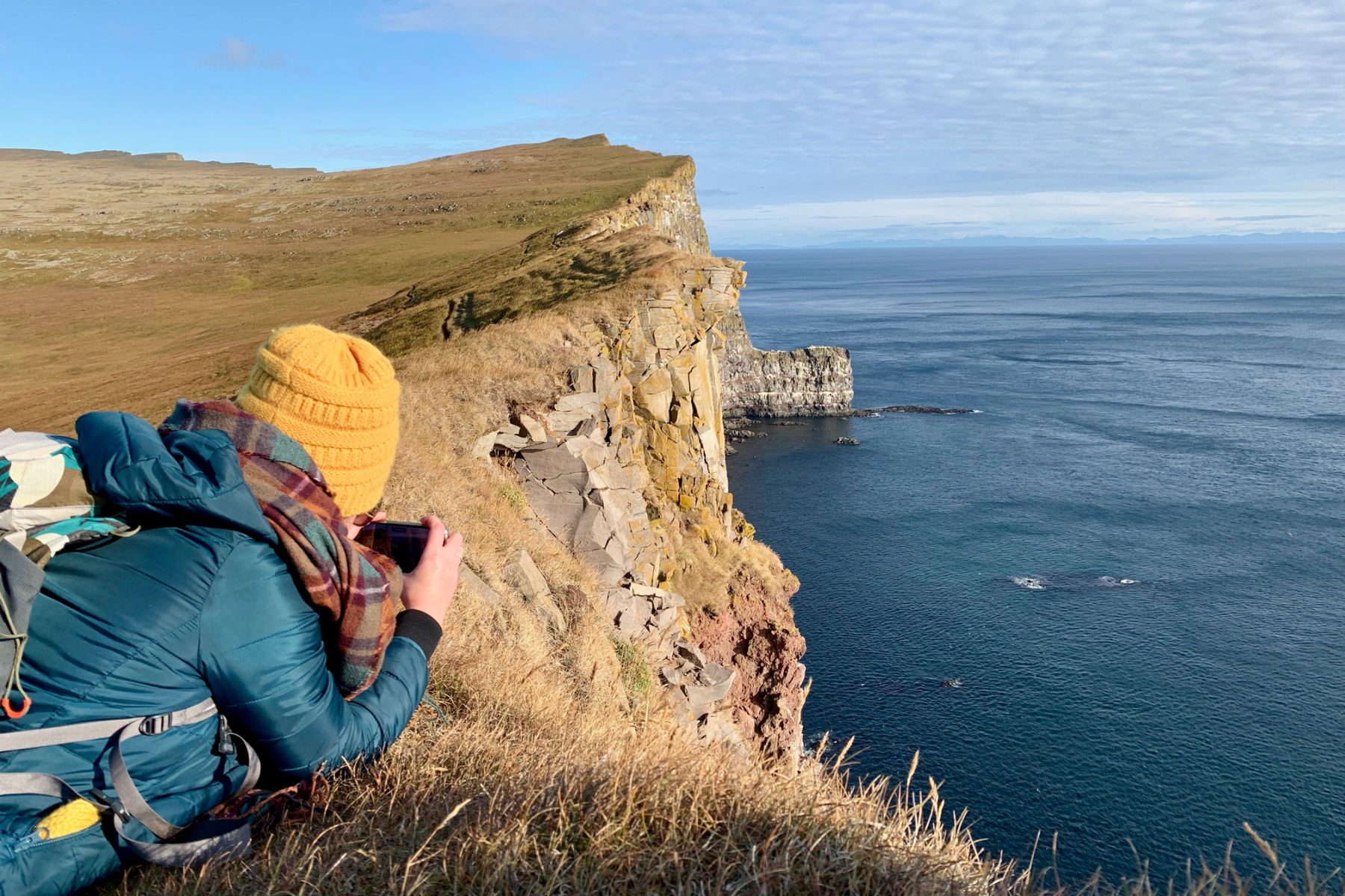 Woman laying on cliff edge taking a picture over the edge