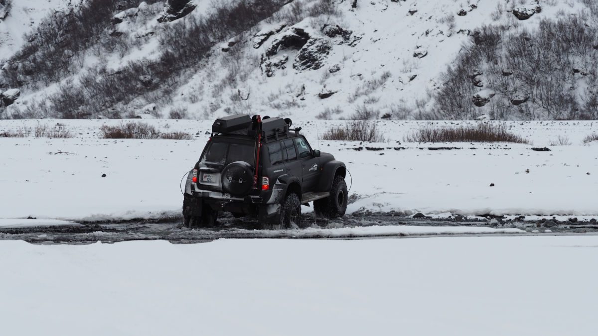 Superjeep driving through a river in the snow